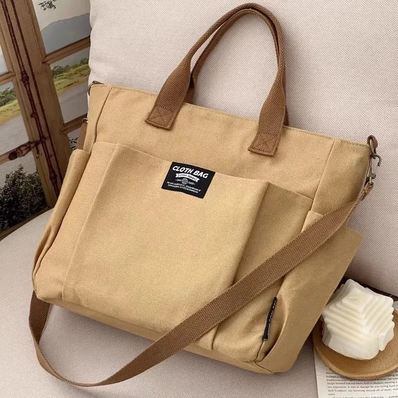 Beige tote bag with brown handles and strap on a light surface.