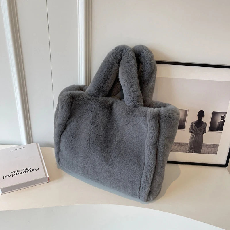 Gray fluffy handbag on a surface with a blurred background