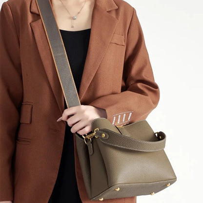 Person holding a brown handbag with a plain background