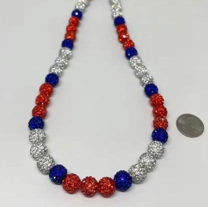 Necklace with blue, orange, and silver beads on a white background Red, white, and blue baseball bling necklace with crystal-inlaid beads from the COGU Ice Collection, designed for athletes and sports fans.