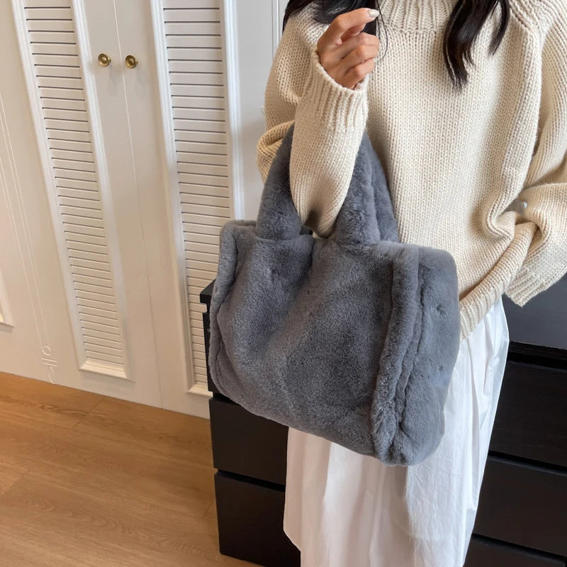 Person holding a gray fluffy bag indoors