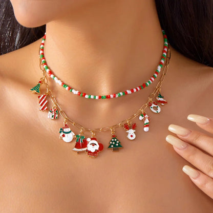 Christmas-themed necklace with Santa Claus and reindeer charms on a model wearing a red top.