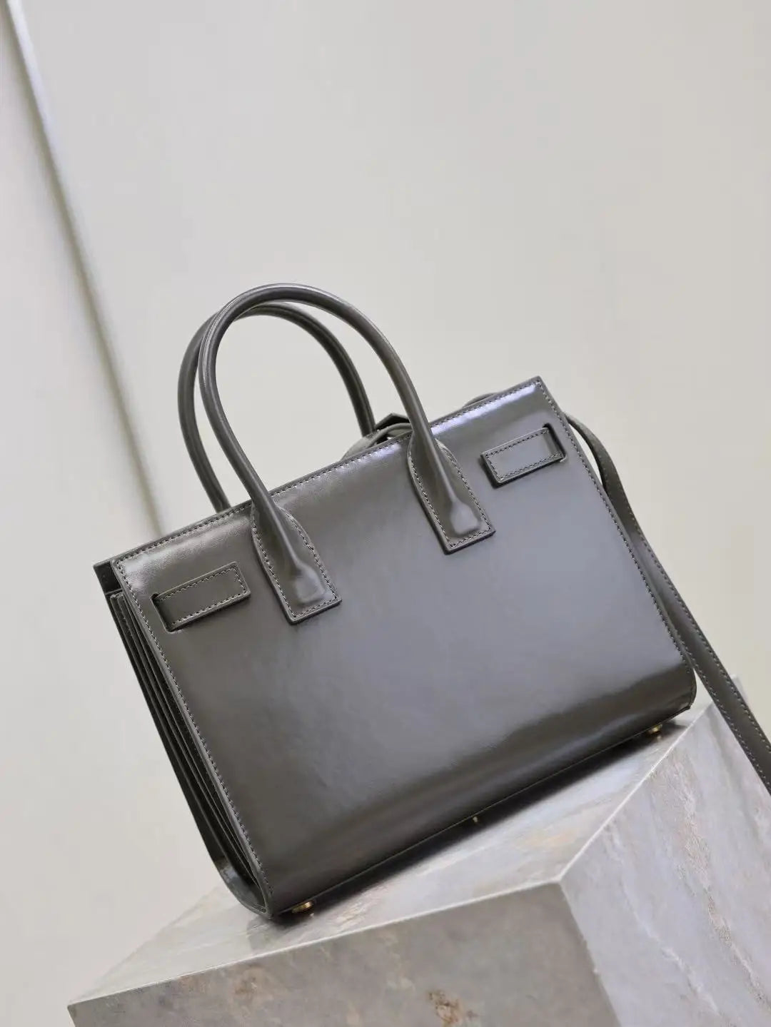 Black handbag on a light gray surface with a neutral background