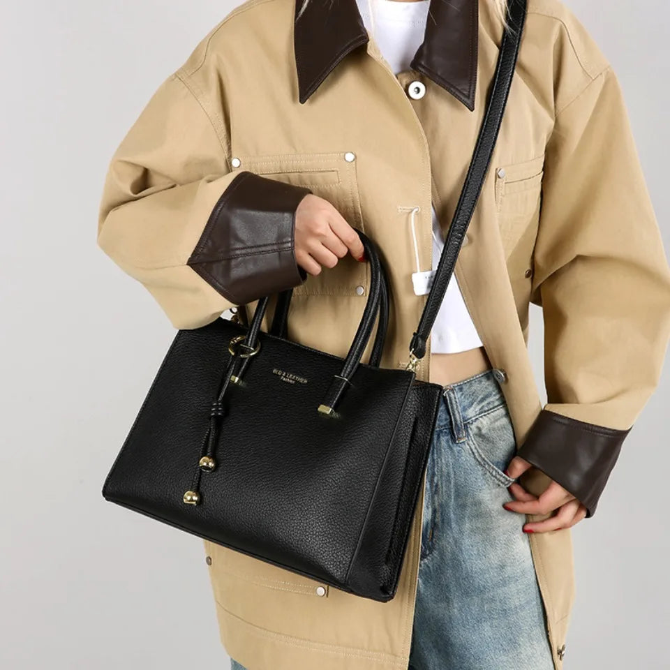 Person holding a black handbag with a neutral background
