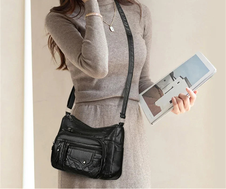 Woman holding a black leather crossbody bag and a tablet.