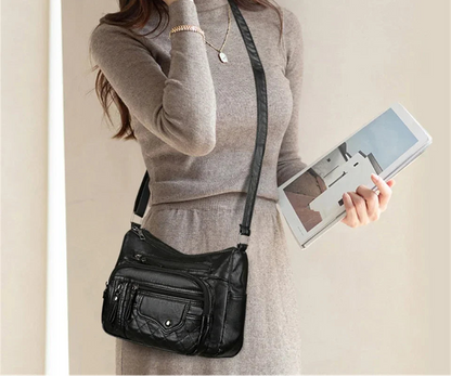 Woman holding a black leather crossbody bag and a tablet.