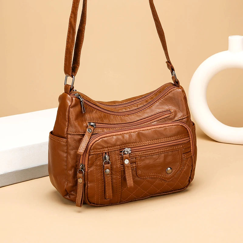 Brown leather handbag with multiple pockets on a beige background