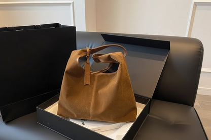Brown handbag in an open black box in the background.