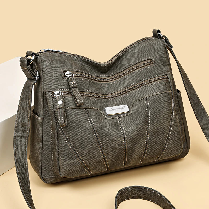 Gray shoulder bag with multiple zippers on a beige background