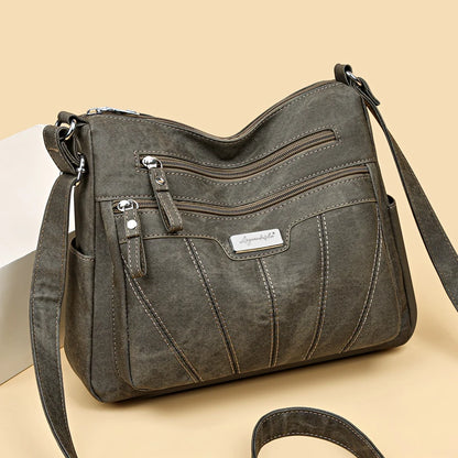 Gray shoulder bag with multiple zippers on a beige background