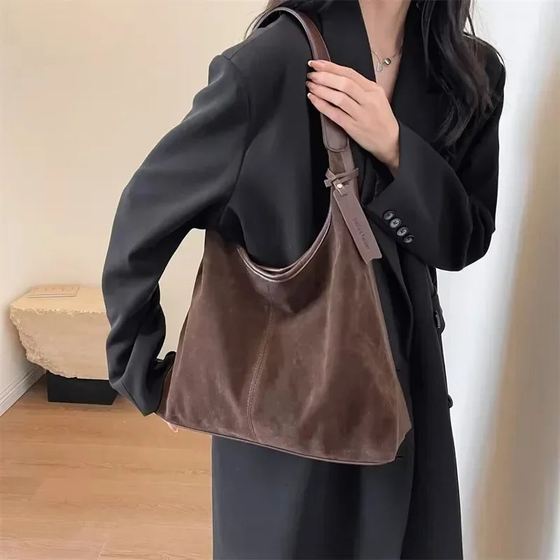 Person holding a brown leather handbag indoors