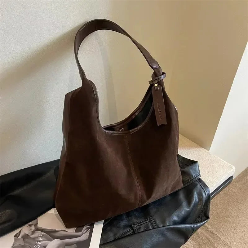 Brown leather handbag on a surface with a neutral background