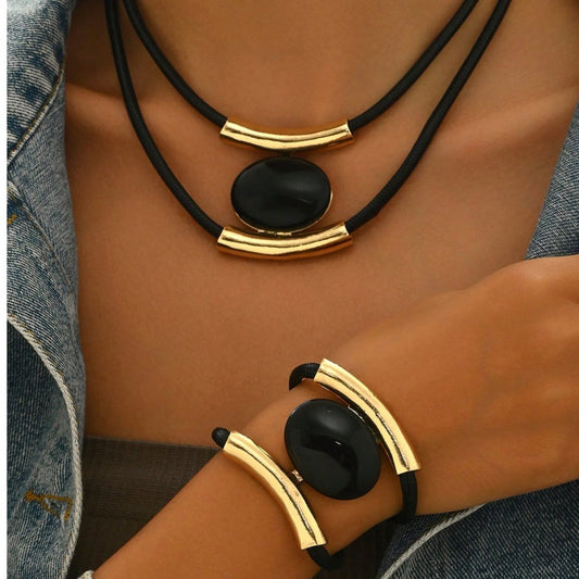 Gold and black jewelry set on a person wearing denim clothing