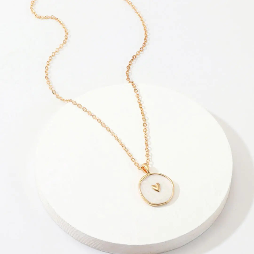 Gold necklace with a circular pendant on a white background