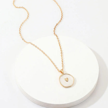 Gold necklace with a circular pendant on a white background