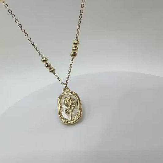video of a gold-tone pendant necklace with a rose-shaped white shell design, on a classic chain.